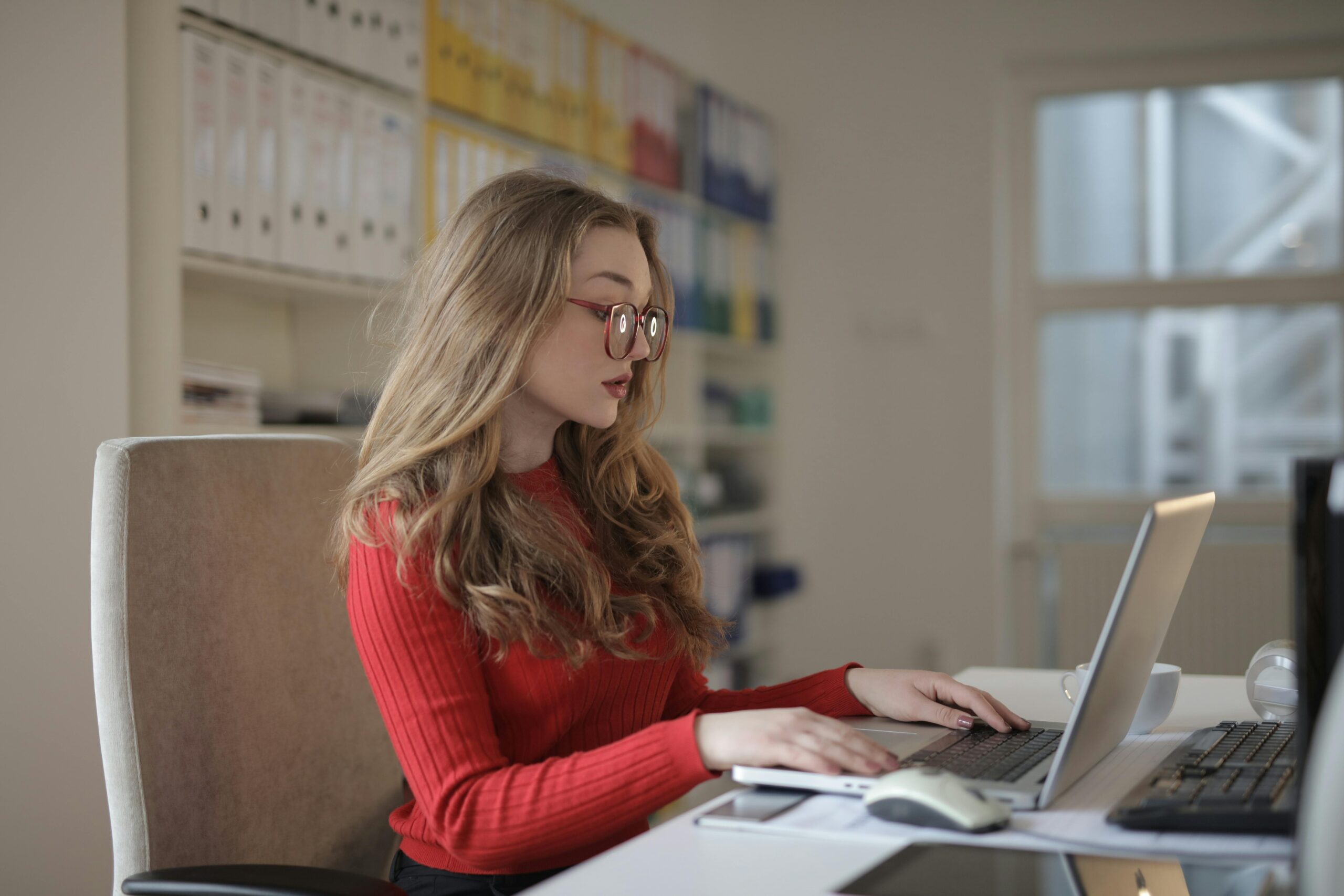 Woman in a office, writing on a laptop. Accountant office.